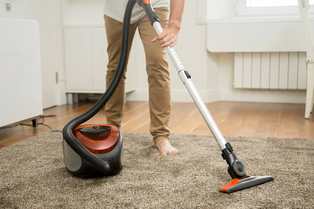 close-up-of-man-vacuum-cleaning-the-carpet-PH58TXG1.jpg